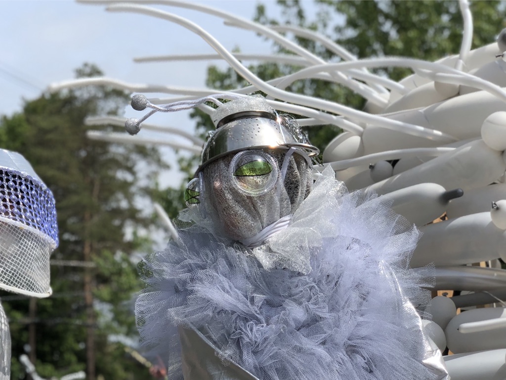 A person in a diy silver alien costume stares ahead.
