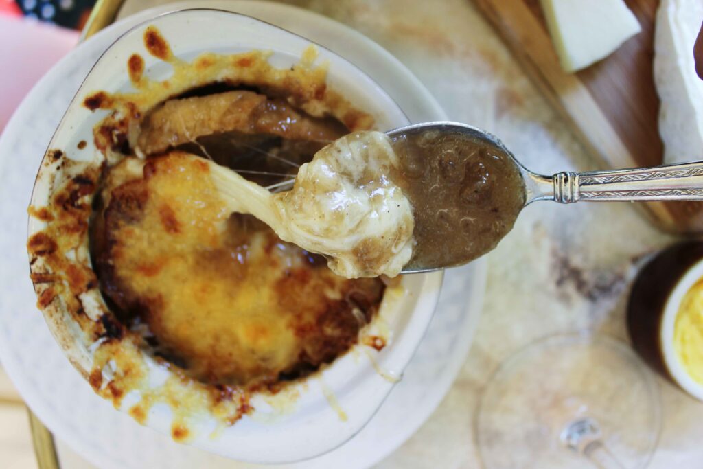 A spoon serves up a melty cheesy bite of french onion soup.