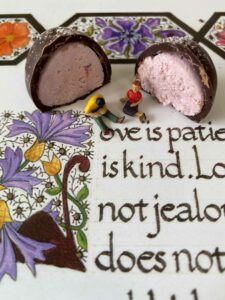 Two figurines are place in front of a halved chocolate with pink filling.