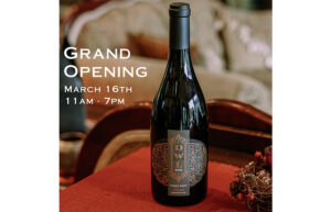 A bottle of wine is placed on a table with red linens. Text says Grand Opening March 16th, 11AM-7PM