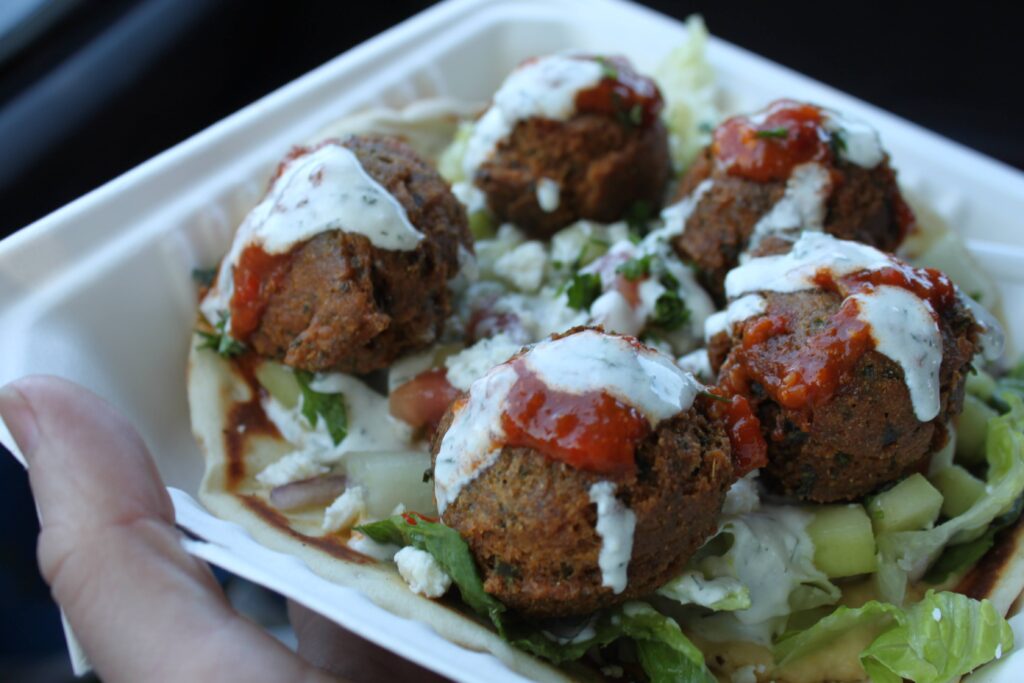 A to-go box filled with falafel stuffed pita.