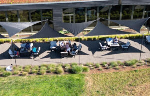 An aerial view of an outdoor patio with tables of people sitting under sunsails.