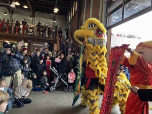 A large crowd watch a dancing dragon.
