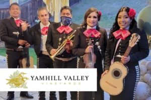A 5 piece mariachi band poses, smiling and holding their instruments.