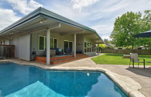 The back patio of a mid-century modern house. There is a pool in the foreground.