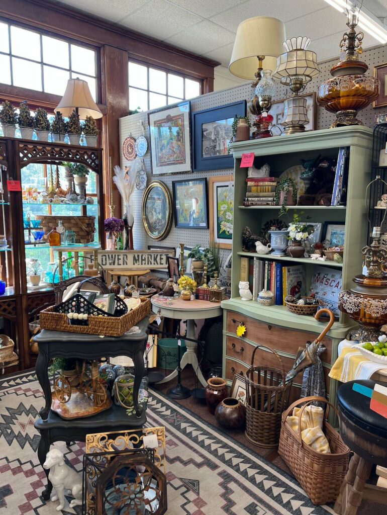 A corner of an antique shop with pictures, knickknacks, lamps and more.