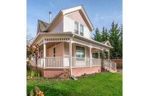 A Victorian style house with muted pinks and a wraparound porch.