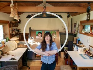 Thea Gahr poses in her art studio at the center of a hanging hoop.