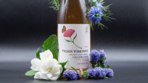 A beautiful bottle of Troon wine with flowers arranged around it.