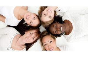 5 women's heads touch each other as they lie down.