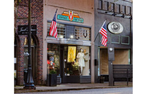 The outside storefront of a vintage store. Two American flags are on either side of a sign that says Vintage on Third.