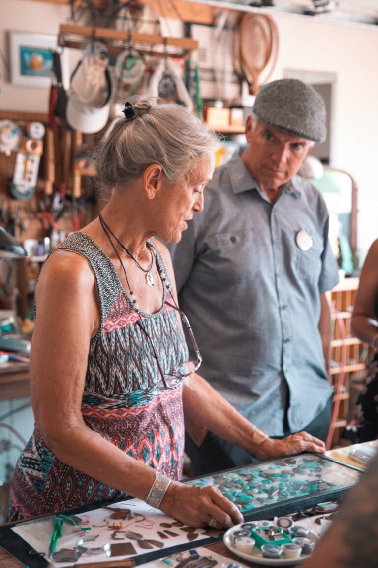 A silversmith shows an onlooker their turquoise collection in a glass case.