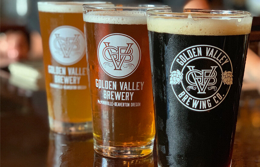 Three pints of beer of varying colors. They have a logo, Golden Valley Brewery.