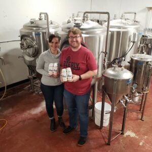 JP and Amelia Bierly hold cans of their beer in in their brewery.