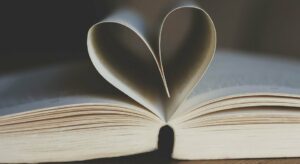 A novel is spread open. Two pages curl into each other, making a heart.