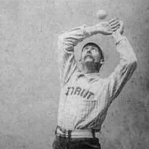 A black and white photo of a man catching a baseball with his bare hands.