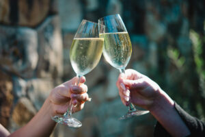 Two glasses of white sparkling wine clink together.