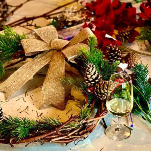 A holiday wreath with a glass of white wine