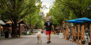 Man with dog walking down the middle of Third Street druing MacFresco 2022